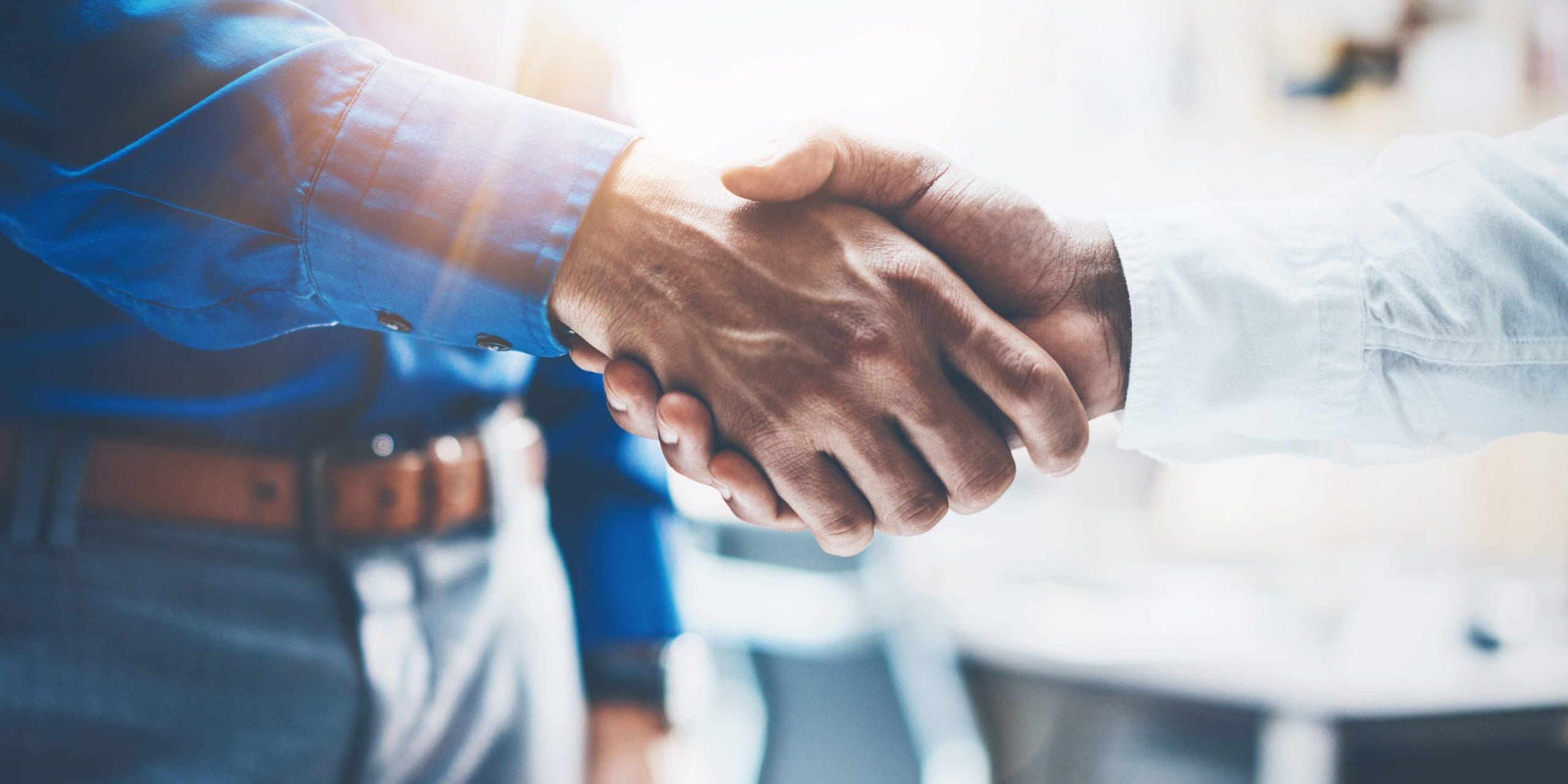 Close up view of business partnership handshake.Concept two businessman handshaking process.Successful deal after great meeting.Horizontal, flare effect, blurred background